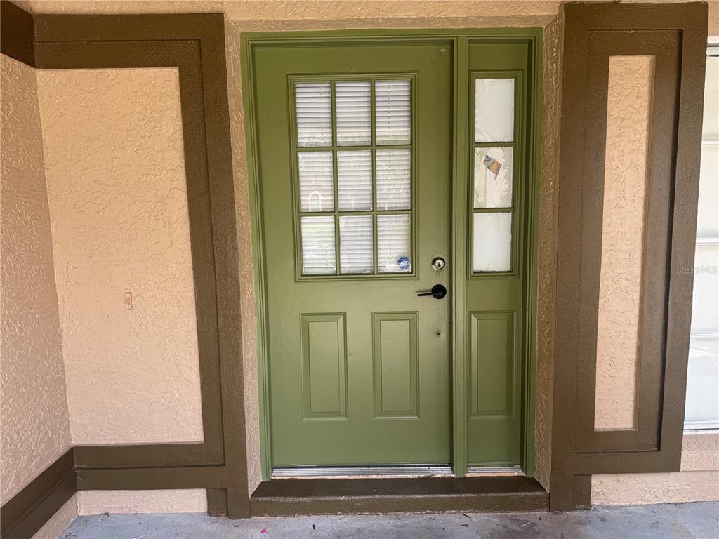A green front door with a window and side light is set within a stucco entryway — 11128 SYLVAN POND CIRCLE, ORLANDO, FL