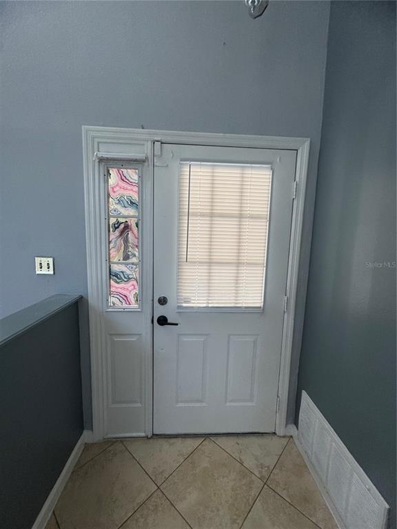 A white exterior door with a sidelight and blinds stands in a tiled entryway — 11128 SYLVAN POND CIRCLE, ORLANDO, FL