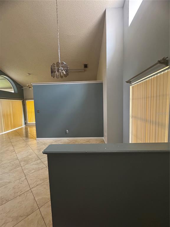 A room with vaulted ceilings, tile flooring, a blue accent wall, and vertical window blinds — 11128 SYLVAN POND CIRCLE, ORLANDO, FL