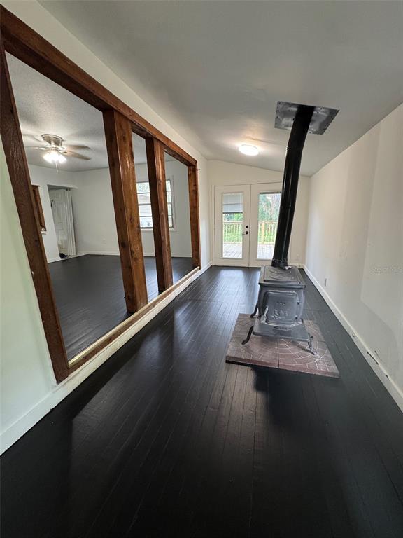 A room with black painted wood floors, a wood-burning stove, and a large wall mirror — 3824 AUTUMN PALM DRIVE, ZEPHYRHILLS, FL