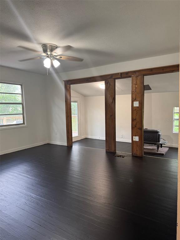 A living room with dark wood floors, a ceiling fan, and a wood-burning stove — 3824 AUTUMN PALM DRIVE, ZEPHYRHILLS, FL