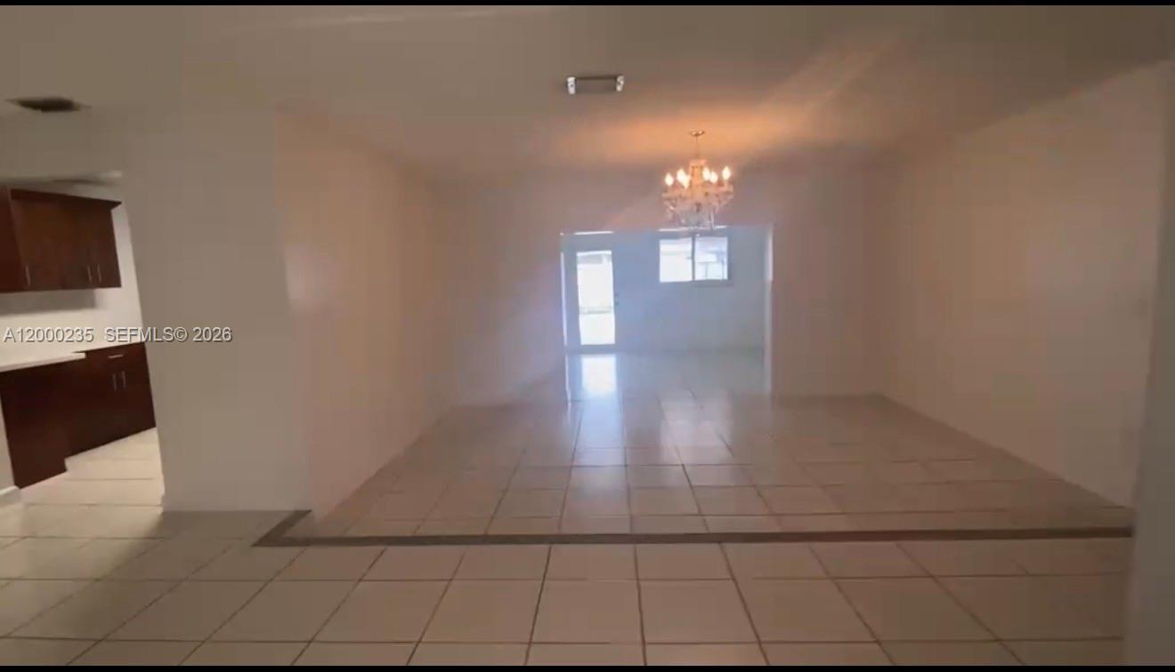 An interior view shows a tiled living area leading to a kitchen and rear doorway — 17335 SW 108th Ct, Miami FL 33157, MIAMI, FL