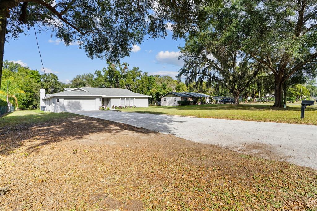 A single-story house with a gray roof and attached garage sits on a grassy lot — 1106 HUMMINGBIRD LANE, BRANDON, FL
