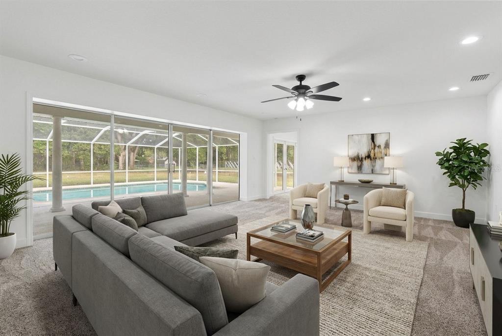 A living room with a grey sectional, two armchairs, a coffee table, and pool views — 1106 HUMMINGBIRD LANE, BRANDON, FL