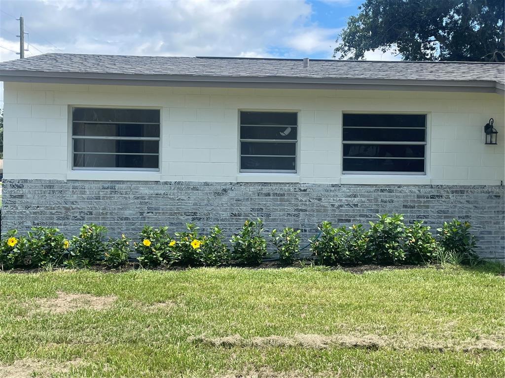 The exterior of a house features white concrete blocks, a brick base, and three jalousie windows — 611 ORANGE AVENUE, LONGWOOD, FL