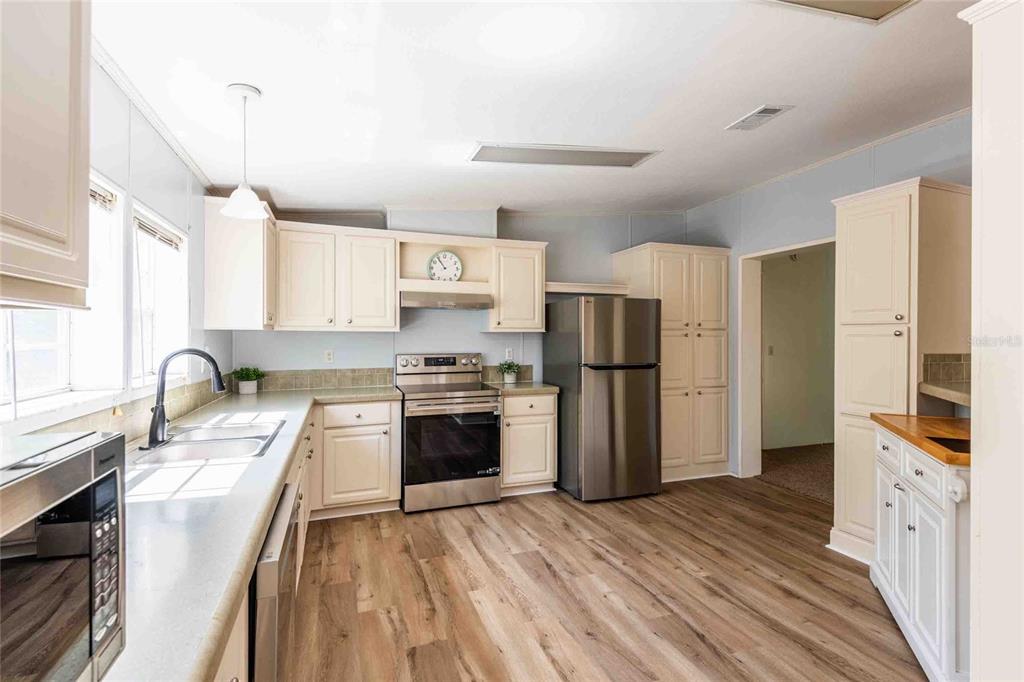 A kitchen with light-colored cabinets, stainless steel appliances, and wood-look flooring — 14221 HURRICANE DRIVE, WEEKI WACHEE, FL