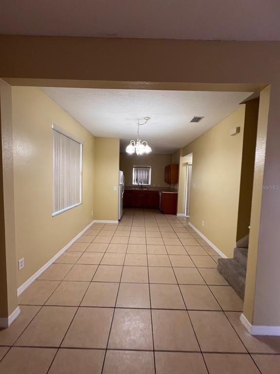 A long, tiled dining area leads into a kitchen with wood cabinets and a chandelier — 201 WATTS LANE UNIT A, KISSIMMEE, FL