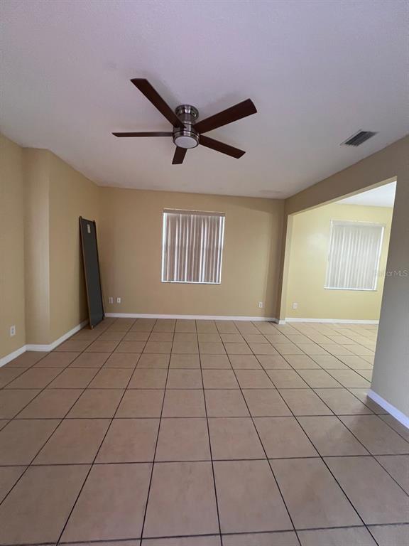 An empty room with tan tile flooring, beige walls, and a ceiling fan — 201 WATTS LANE UNIT A, KISSIMMEE, FL