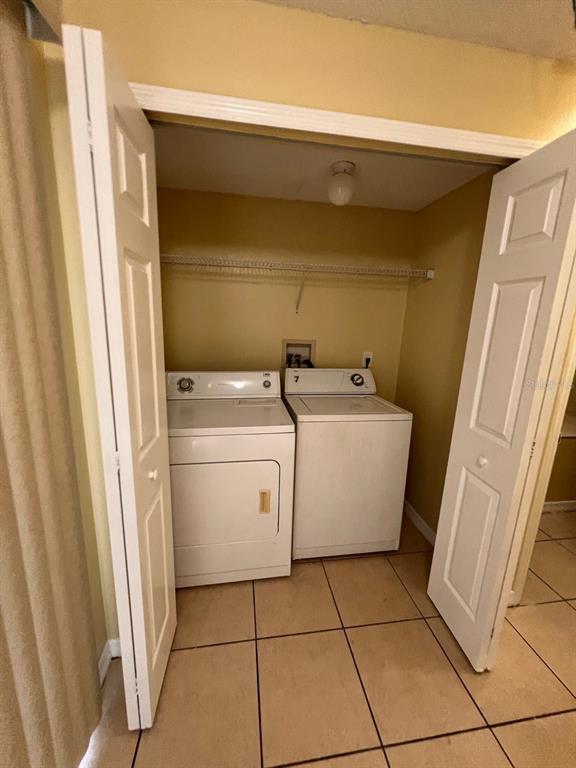 A laundry closet contains a white washer and dryer set on a tiled floor — 201 WATTS LANE UNIT A, KISSIMMEE, FL