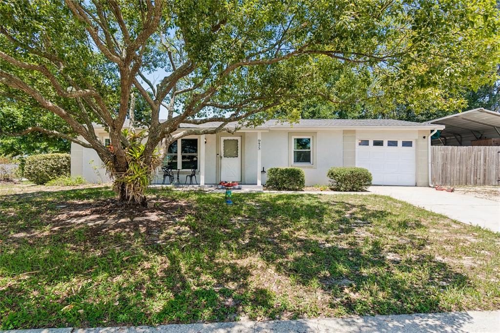 A single-story house with a white garage, a front door, and a large tree — 9473 BAYSIDE COURT, SPRING HILL, FL