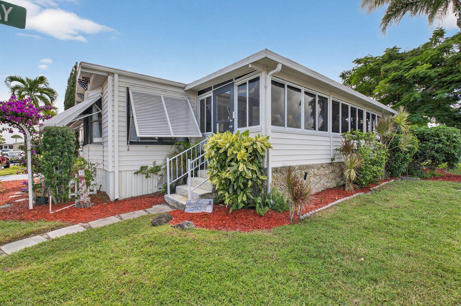 A single-story mobile home with white siding, a screened-in porch, and a landscaped front yard — 50012 Hacha, Boynton Beach FL 33436, BOYNTON BEACH, FL