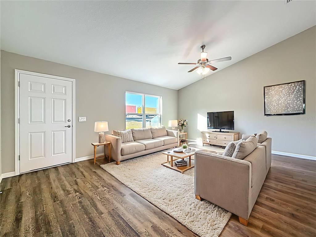A living room features light gray walls, wood-look flooring, a ceiling fan, and two sofas — 14805 SW 32ND PLACE, OCALA, FL