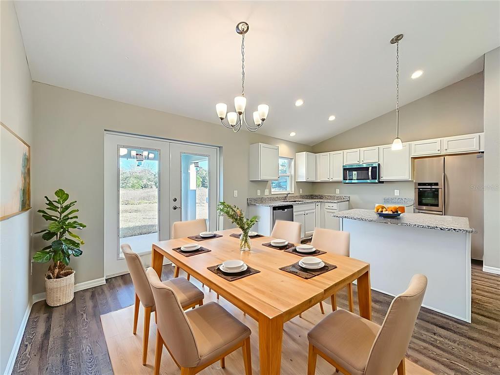 A dining area with a wooden table and chairs sits adjacent to a modern kitchen — 14805 SW 32ND PLACE, OCALA, FL