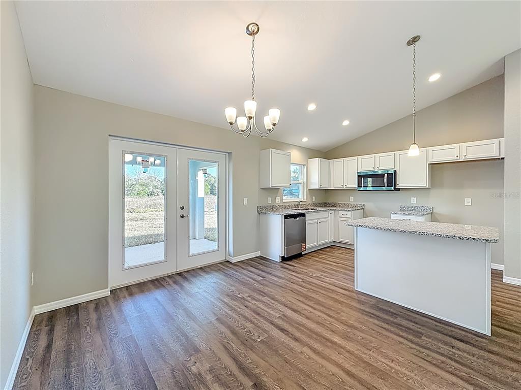 A kitchen and dining area feature white cabinets, granite countertops, and wood-look flooring — 14805 SW 32ND PLACE, OCALA, FL