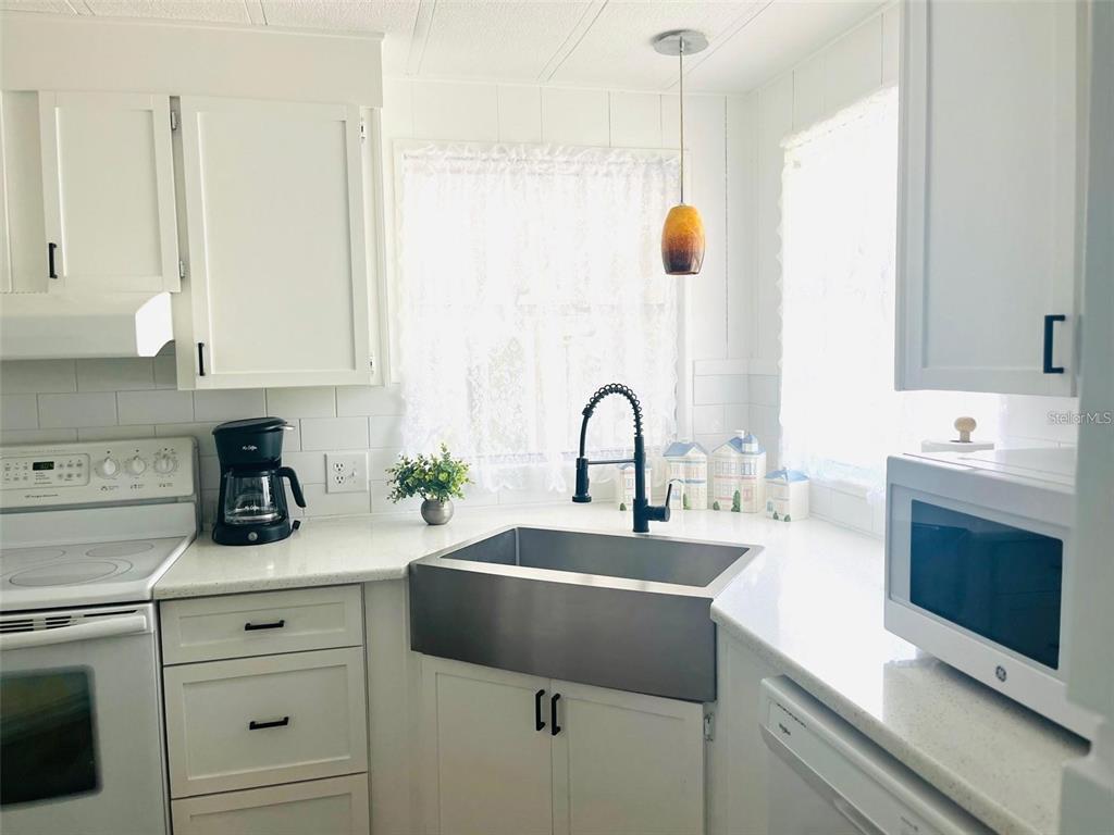 A kitchen features white cabinetry, a stainless steel farmhouse sink, and a black faucet — 33 BOBCAT TRAIL, WILDWOOD, FL