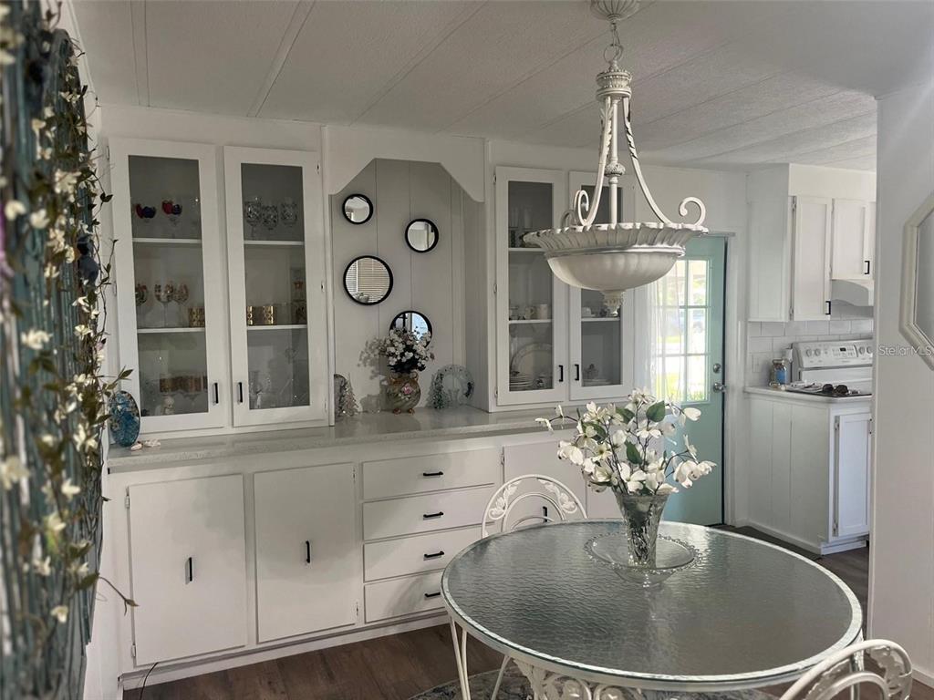 A dining area features white cabinetry, a glass-topped table, and a decorative chandelier — 33 BOBCAT TRAIL, WILDWOOD, FL