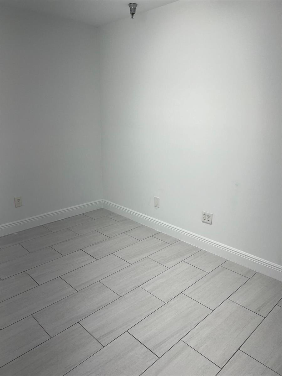 An empty room with white walls, white baseboards, and light gray wood-look tile flooring — 1312 Commerce Lane # 15b, Jupiter FL 33458, JUPITER, FL