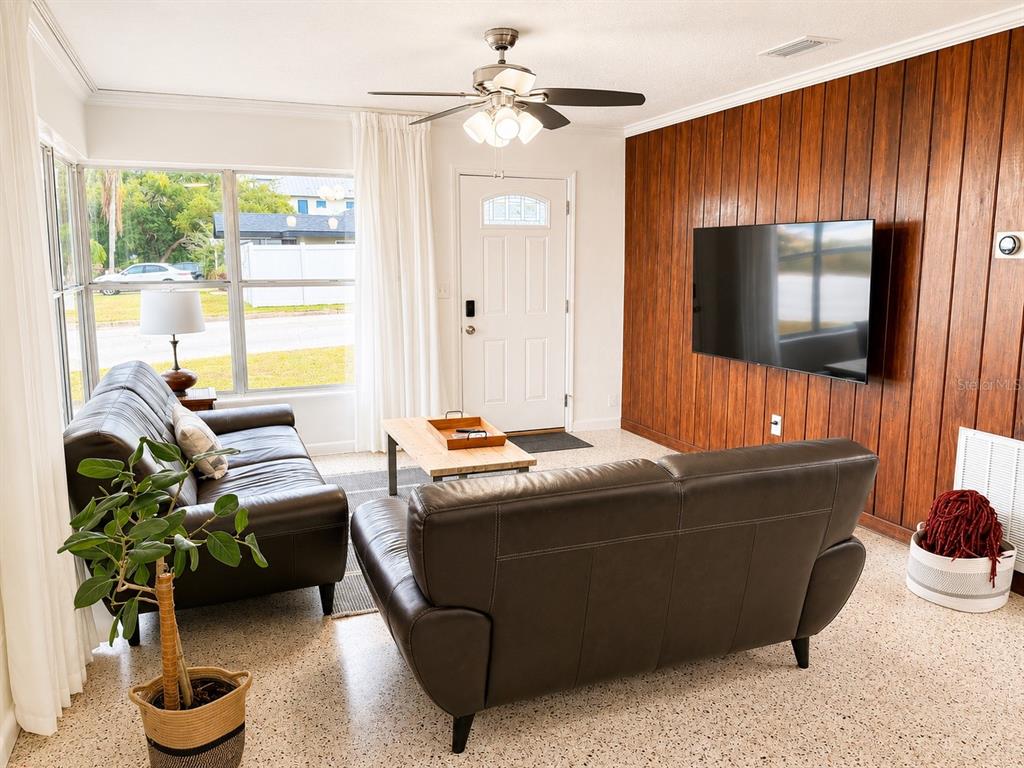A living room features dark leather sofas, a wood-paneled accent wall, and a ceiling fan — 13619 LAKE BOULEVARD, WINTER GARDEN, FL