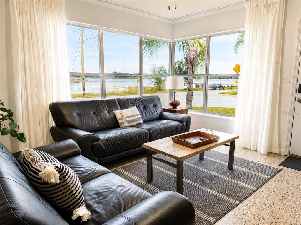 A living room features two black leather sofas, a wooden coffee table, and large windows — 13619 LAKE BOULEVARD, WINTER GARDEN, FL