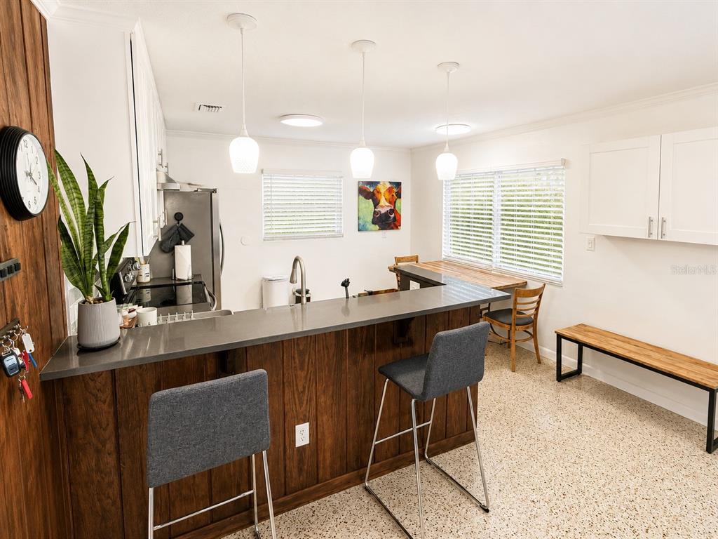 A kitchen with a wood-paneled breakfast bar, gray countertops, white cabinets, and pendant lighting — 13619 LAKE BOULEVARD, WINTER GARDEN, FL