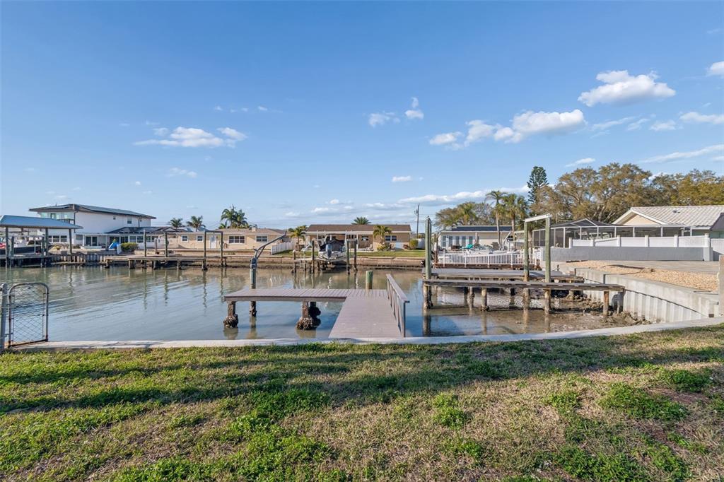 A grassy backyard overlooks a canal with a wooden dock and boat slips — 4415 CLEARWATER HARBOR DRIVE N, LARGO, FL