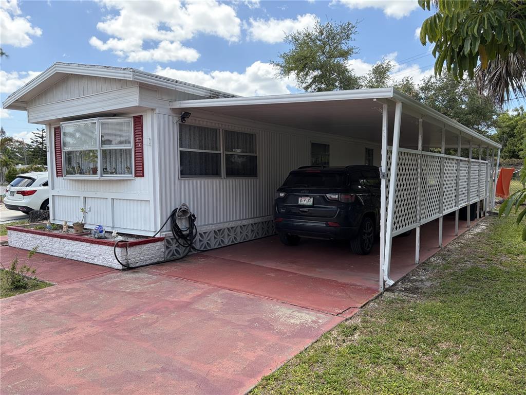 A white mobile home features a red-painted driveway, a carport, and a small front planter — 4833 BOCA RATON AVENUE, SARASOTA, FL