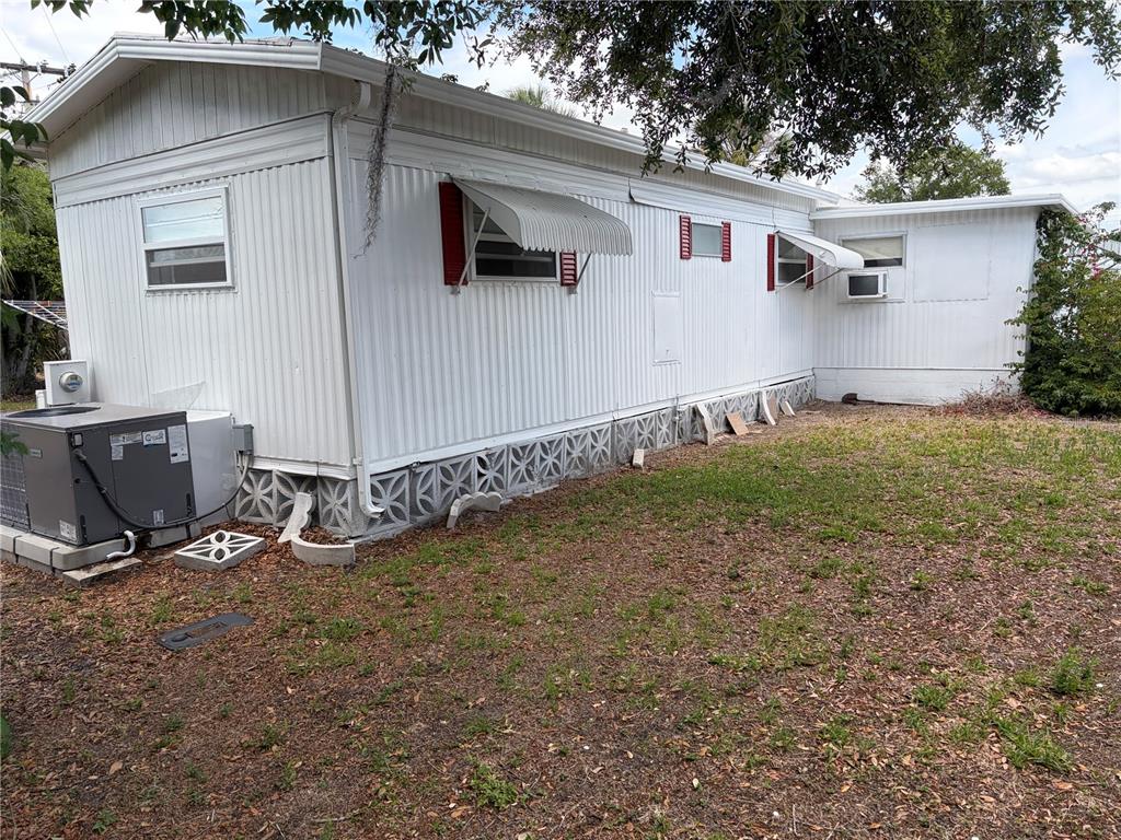 The exterior of a white mobile home features metal siding, window awnings, and lattice skirting — 4833 BOCA RATON AVENUE, SARASOTA, FL