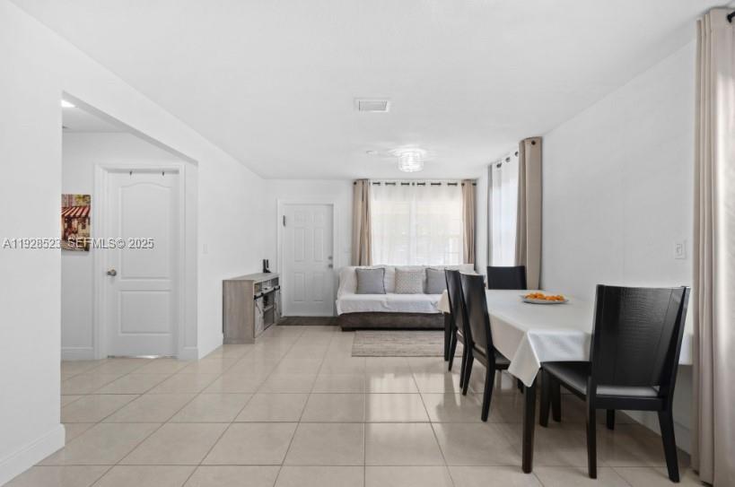 A dining area with a table and chairs opens into a living room with tile floors — 701 NE 6th St, Hallandale Beach FL 33009, HALLANDALE BEACH, FL