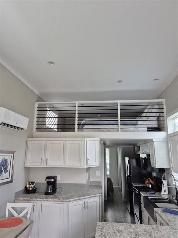 A kitchen with white cabinets and granite countertops sits below a loft bedroom with railings — 0 HIGHWAY 630 E UNIT 320, LAKE WALES, FL