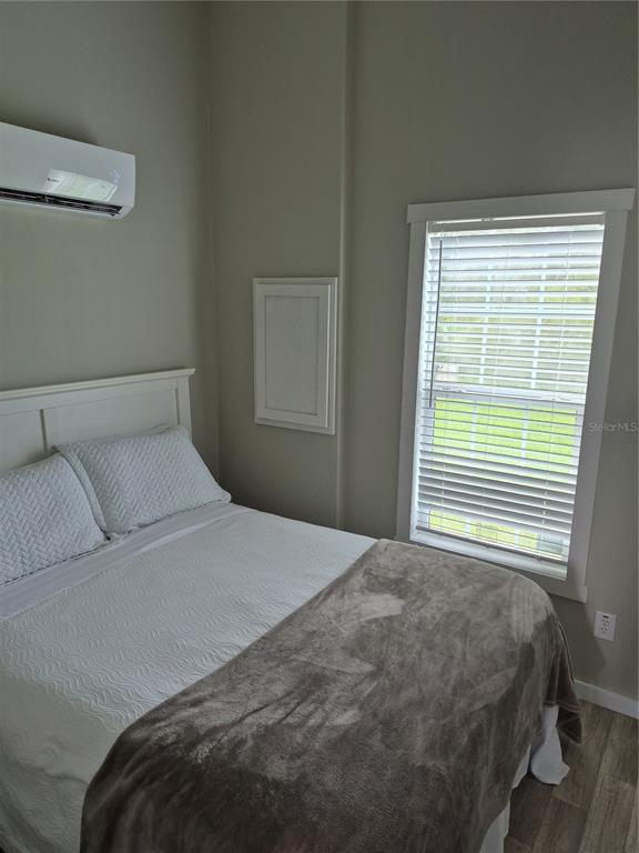 A bedroom features a white bed, a wall-mounted air conditioner, and a window with blinds — 0 HIGHWAY 630 E UNIT 320, LAKE WALES, FL