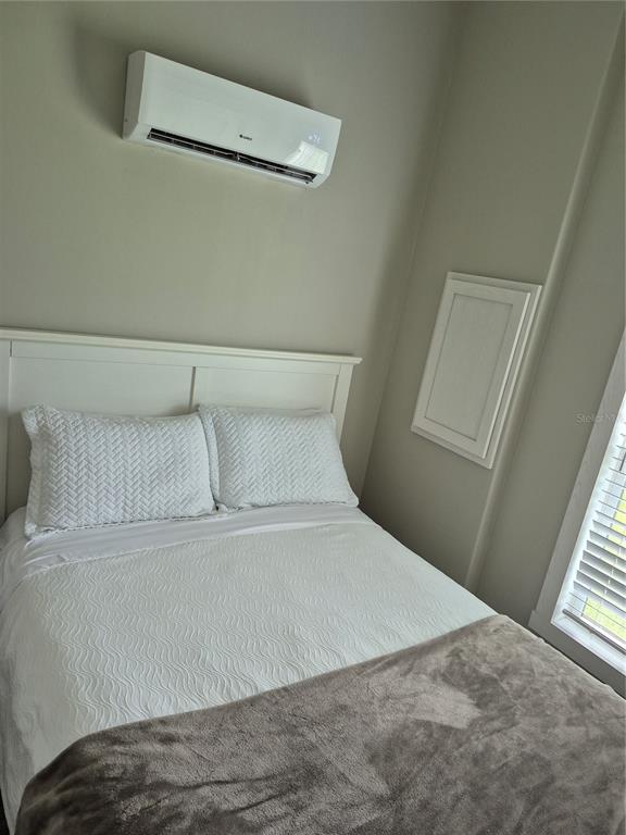 A bedroom features a white bed, a wall-mounted air conditioner, and a small access panel — 0 HIGHWAY 630 E UNIT 320, LAKE WALES, FL