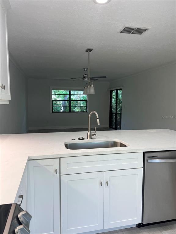 A kitchen island with a stainless steel sink faces a living area with windows — 4044 CORKWOOD COURT, PALM HARBOR, FL