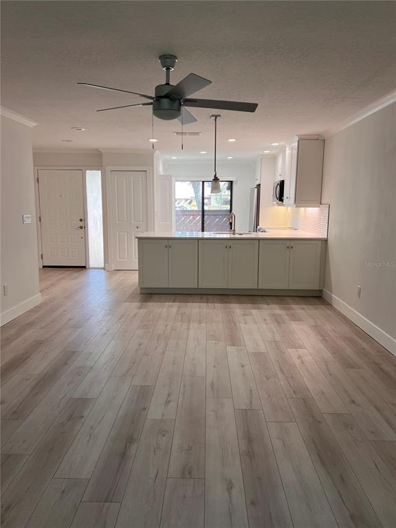 A kitchen with white cabinets and a center island overlooks a living area with wood-look flooring — 4044 CORKWOOD COURT, PALM HARBOR, FL