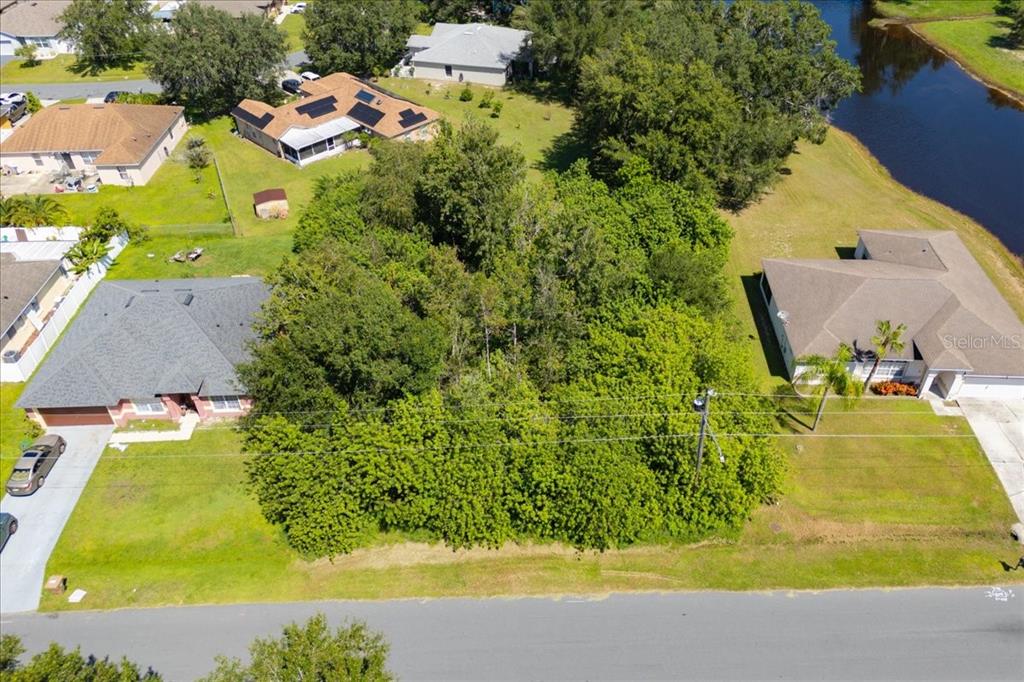 An aerial view shows a vacant, tree-covered lot situated between two residential houses — 0 CANNES DRIVE, KISSIMMEE, FL