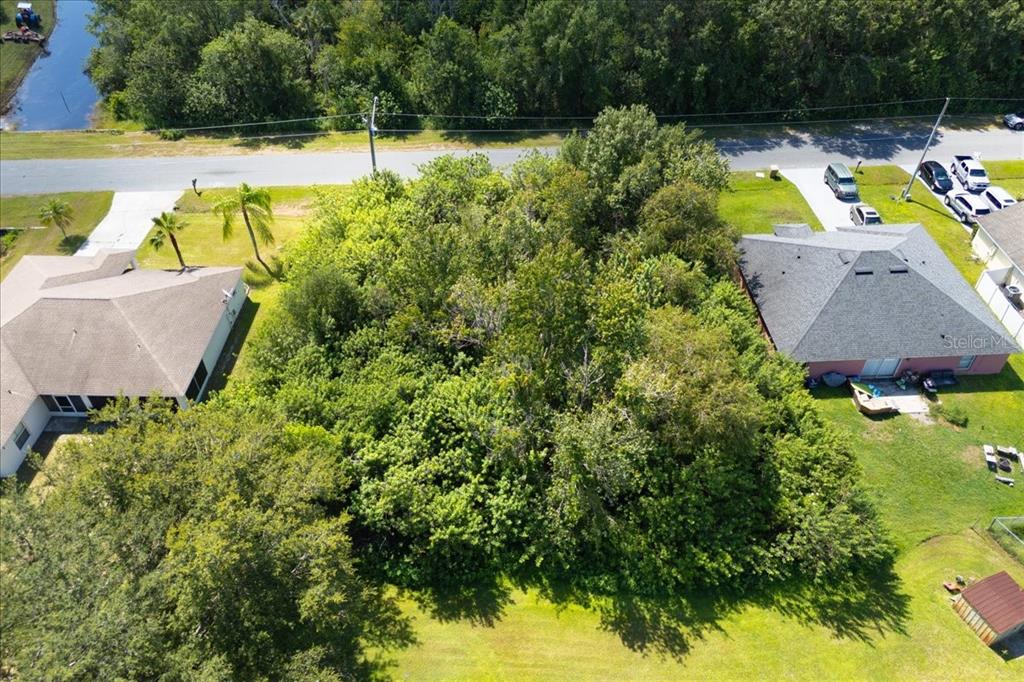 An aerial view shows a heavily wooded vacant lot situated between two residential houses — 0 CANNES DRIVE, KISSIMMEE, FL