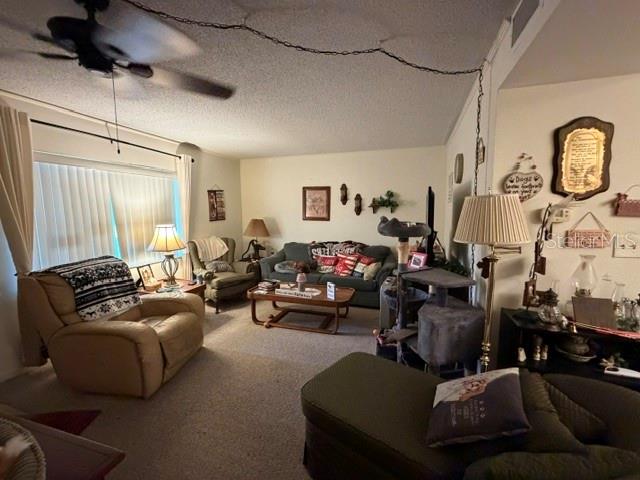 A living room features a beige recliner, a sofa with patterned pillows, and a ceiling fan — 1130 N LAKE PARKER AVENUE UNIT A208, LAKELAND, FL
