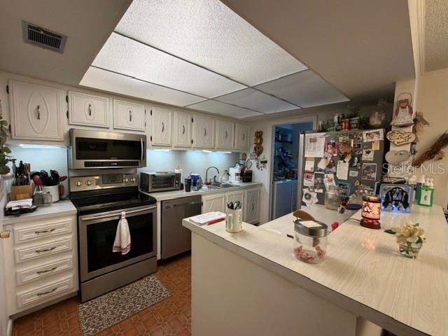 A kitchen features white cabinetry, a stainless steel stove, and a breakfast bar — 1130 N LAKE PARKER AVENUE UNIT A208, LAKELAND, FL
