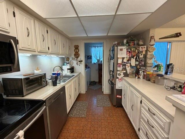 A kitchen features white cabinets, a stainless steel toaster oven, and a tiled floor — 1130 N LAKE PARKER AVENUE UNIT A208, LAKELAND, FL