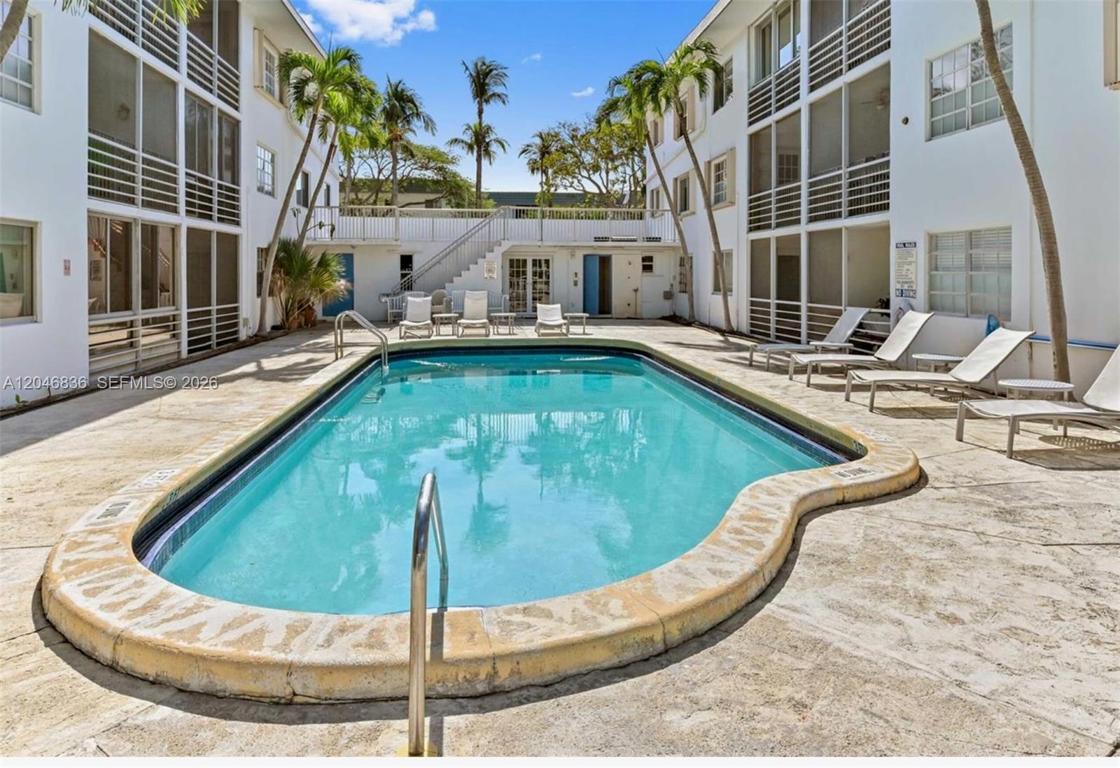 An outdoor swimming pool is surrounded by a concrete deck and multi-story apartment buildings — 251 Galen Dr # 302, Key Biscayne FL 33149, KEY BISCAYNE, FL