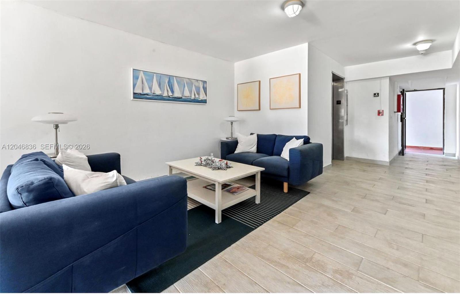 A living area features two blue sofas, a white coffee table, and light wood flooring — 251 Galen Dr # 302, Key Biscayne FL 33149, KEY BISCAYNE, FL