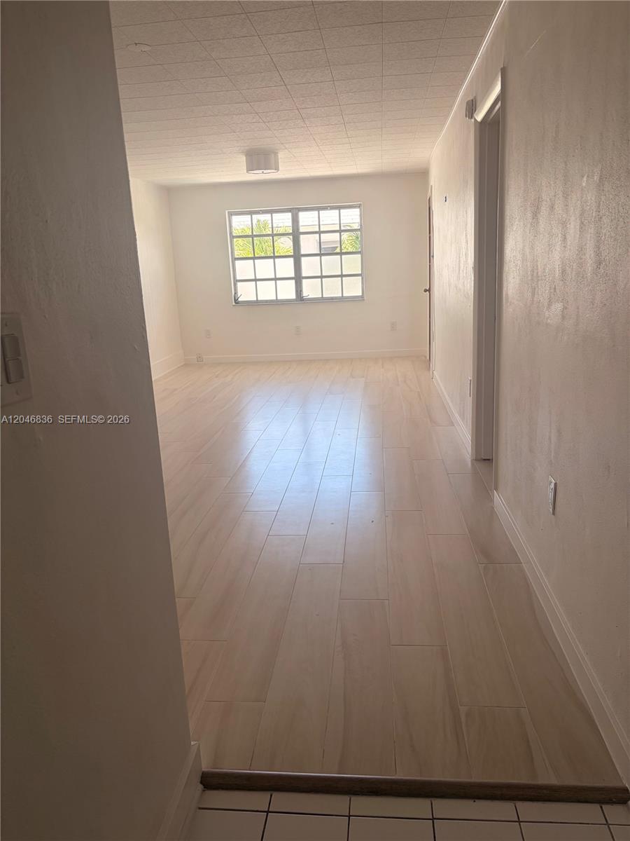 An empty room features light-colored wood-look flooring, white walls, and a single window — 251 Galen Dr # 302, Key Biscayne FL 33149, KEY BISCAYNE, FL