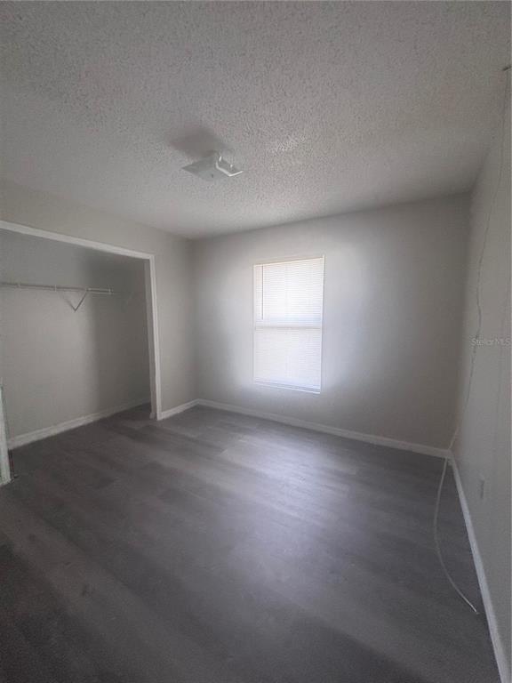 An empty bedroom features light gray walls, wood-look flooring, a window with blinds, and a closet — 624 JAGUAR COURT, POINCIANA, FL
