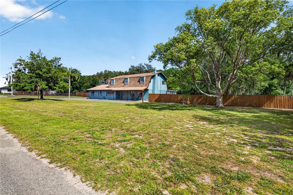 A two-story blue house with a brown roof sits behind a large grassy yard — 9400 SAVOY COURT, NEW PORT RICHEY, FL
