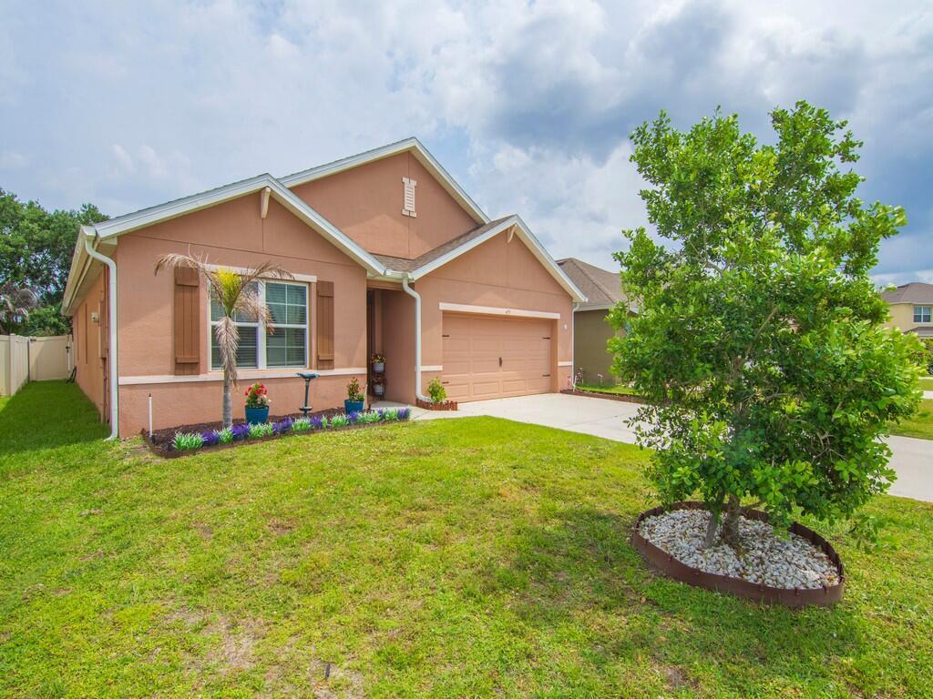 A single-story tan house with a two-car garage and a front yard with landscaping — 475 SW Moray Dr Drive, Palm Bay FL 32908, PALM BAY, FL