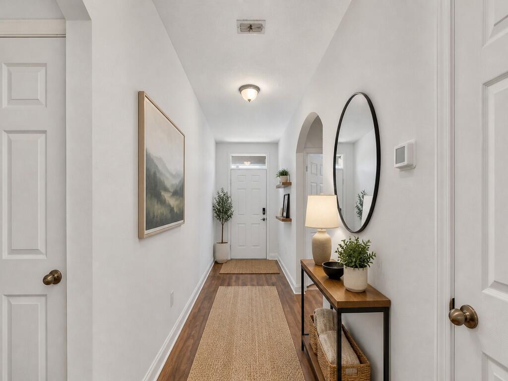 A bright hallway features wood-look flooring, a console table, a mirror, and a front door — 475 SW Moray Dr Drive, Palm Bay FL 32908, PALM BAY, FL