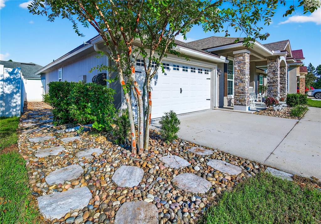 A single-story house exterior features a two-car garage, stone columns, and a stone-paved walkway — 86434 MOONLIT WALK CIRCLE, YULEE, FL