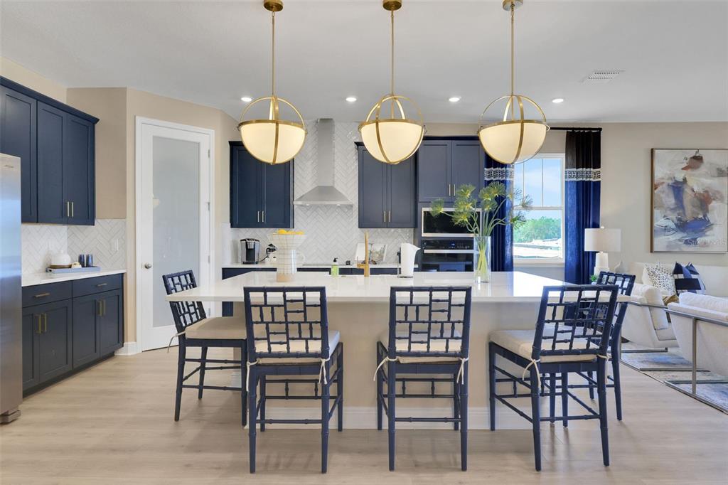 A kitchen features navy blue cabinets, a white island with bar stools, and three pendant lights — 17320 WILD DAISY DRIVE, WINTER GARDEN, FL