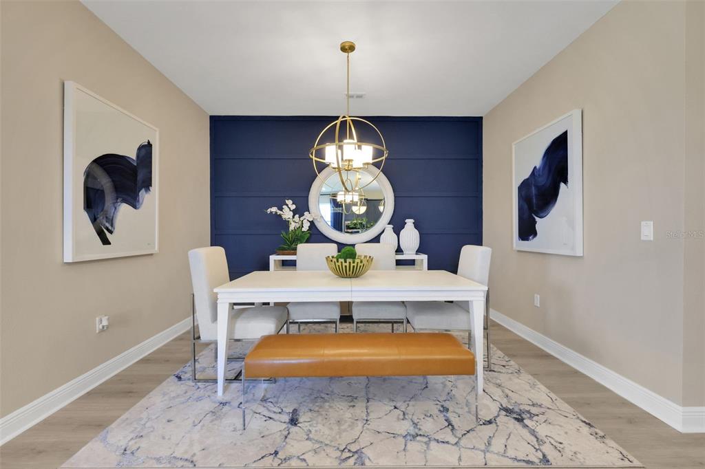A dining room features a navy blue accent wall, white table, and gold orb chandelier — 17320 WILD DAISY DRIVE, WINTER GARDEN, FL