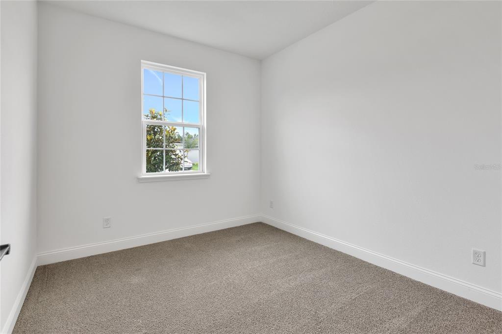 An empty bedroom features white walls, beige carpeting, and a single window — 198 ENCLAVE AVENUE, PALM COAST, FL