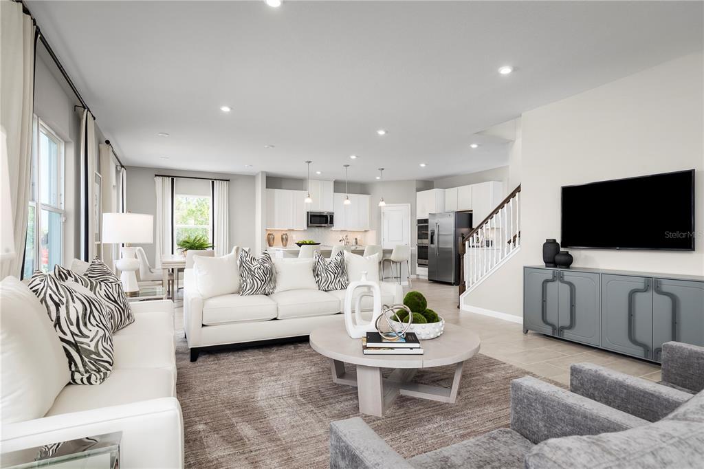 A bright, open-concept living room and kitchen area with white sofas and a gray console — 7348 SW 107TH LANE, OCALA, FL